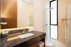 A modern bathroom with a marble sink, a large mirror, and a glass shower enclosure.