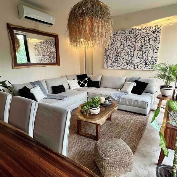A modern living room with a grey sectional sofa, a wooden coffee table, and a patterned wall.