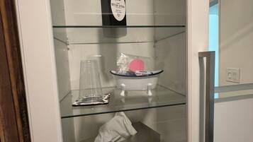 A bathroom with a glass shelf containing a bottle of lotion, a soap dish, and a tissue box.