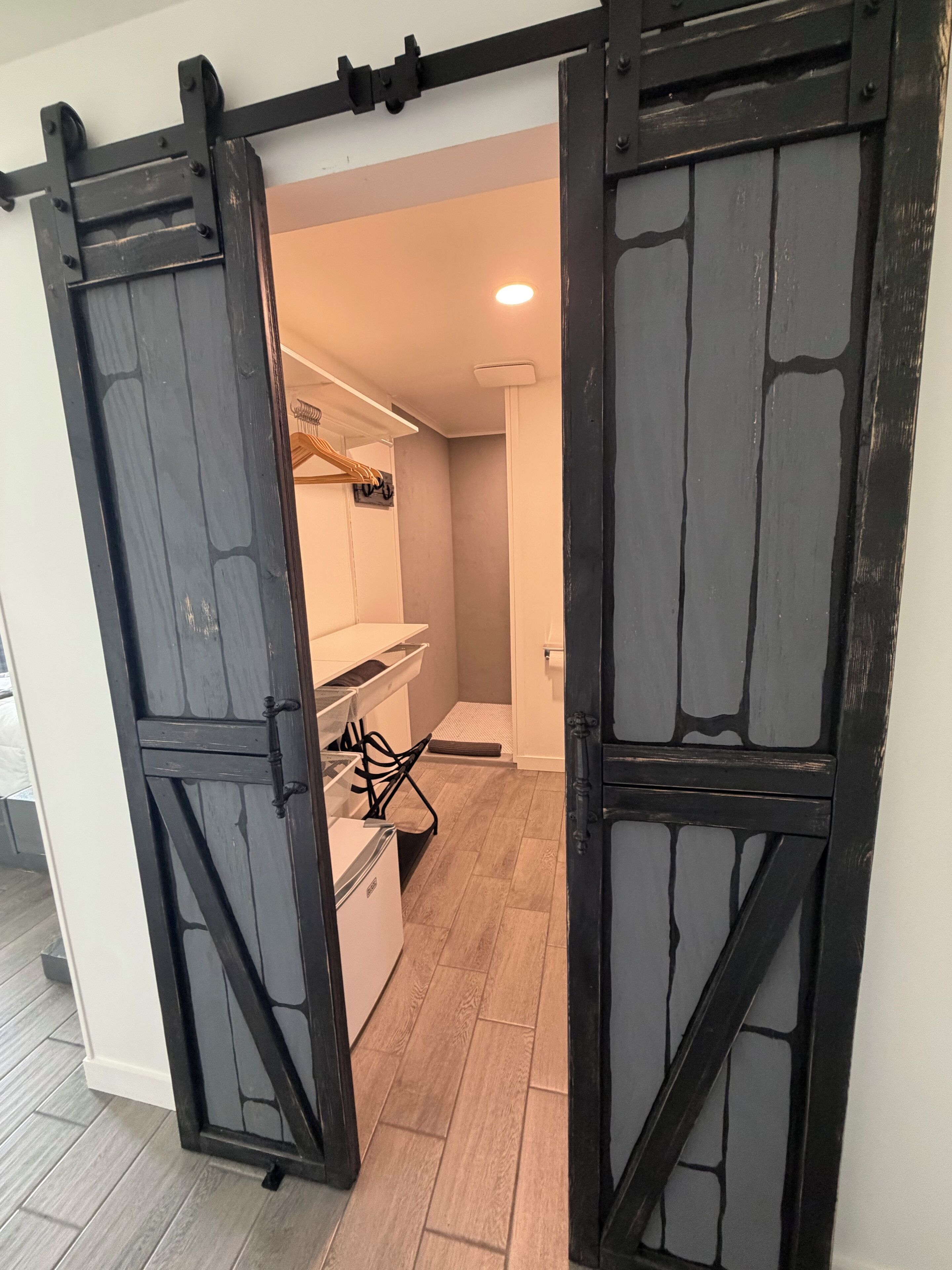 Une pièce avec une porte coulissante de style grange, une armoire blanche, une petite table blanche et une chaise noire.