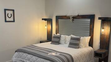 A neatly made bed with a striped blanket, a wooden headboard with a cow head decoration, and two bedside tables with lights.