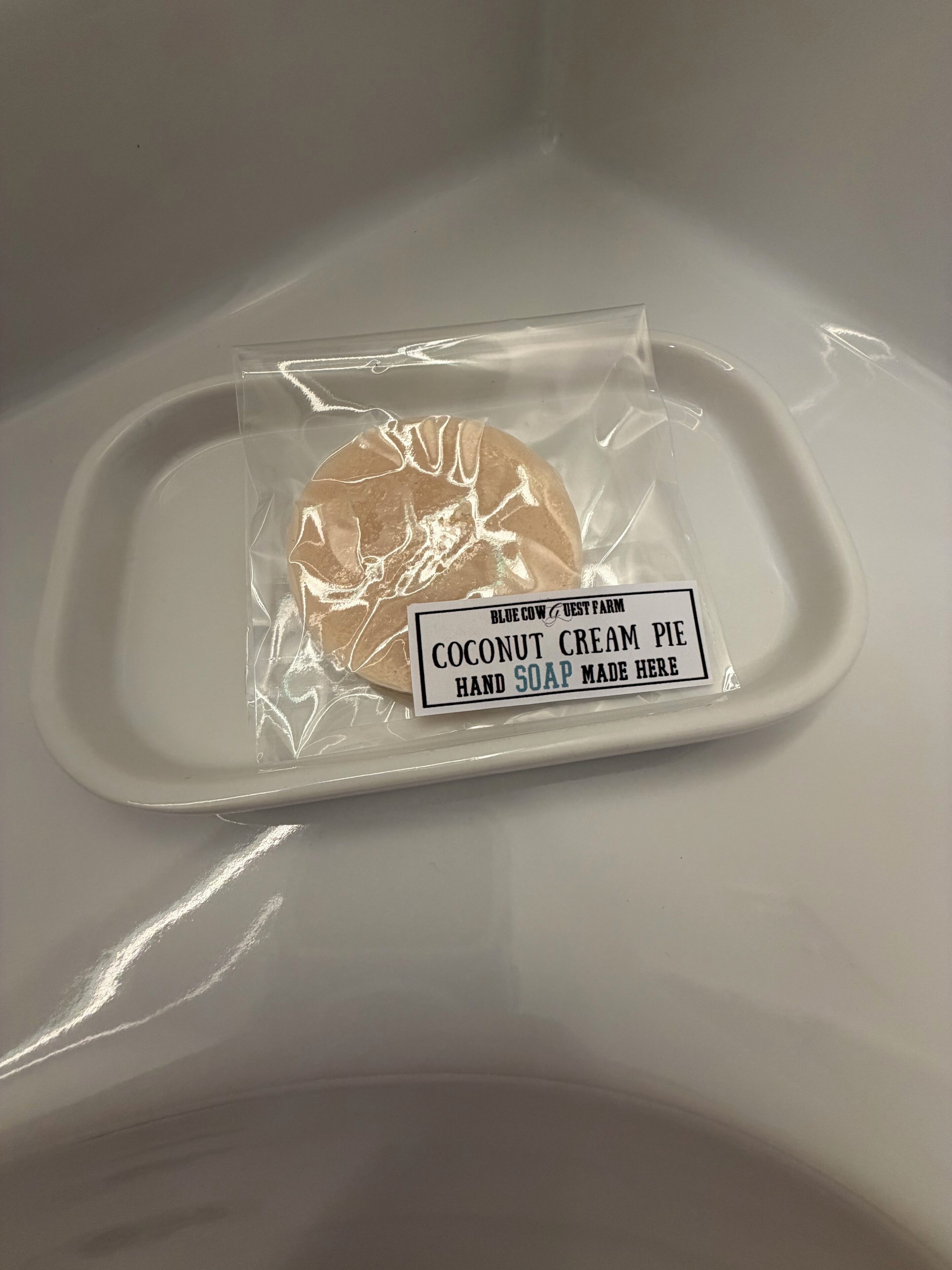 A hand soap package labeled 'Blue Cow & Guest Farm Coconut Cream Pie Hand Soap Made Here' on a white tray.