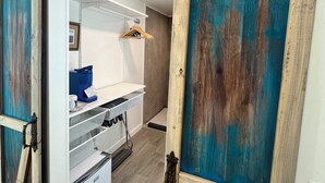 Ein Zimmer mit einer Schiebetür im Scheunenstil, einem weißen Kleiderschrank, einem kleinen Schreibtisch und einer Kleiderstange.