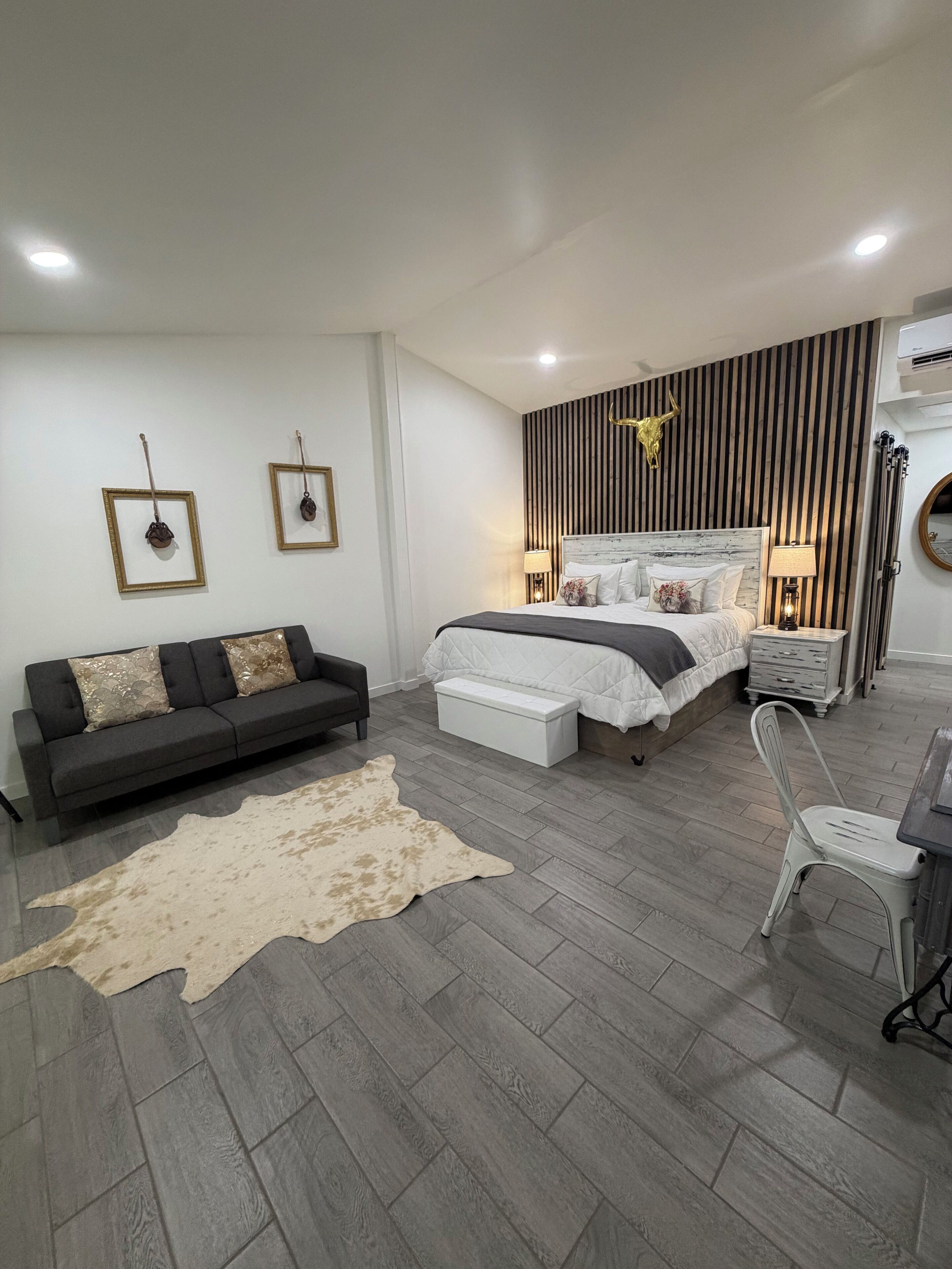 Une chambre moderne avec un lit, un canapé, un bureau et un tapis en peau de vache.