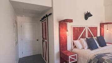 Un dormitorio con cama, aire acondicionado instalado en la pared, cabecero de madera, lámpara de pared y una puerta de estilo rústico.