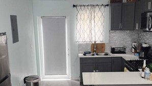 A modern kitchen with grey cabinetry, a central island, and a stainless steel refrigerator. - Charming 2-bedroom apartment with WiFi, AC in fantastic eastern Nassau (Nassau)
