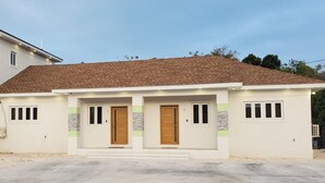 A two-story house with a brown tiled roof, two front doors, and small windows. - Charming 2-bedroom apartment with WiFi, AC in fantastic eastern Nassau (Nassau)