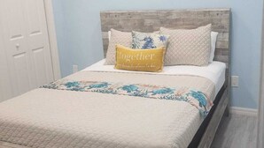 A bedroom with a wooden bed frame, a white bedspread, and a fluffy rug. - Charming 2-bedroom apartment with WiFi, AC in fantastic eastern Nassau (Nassau)