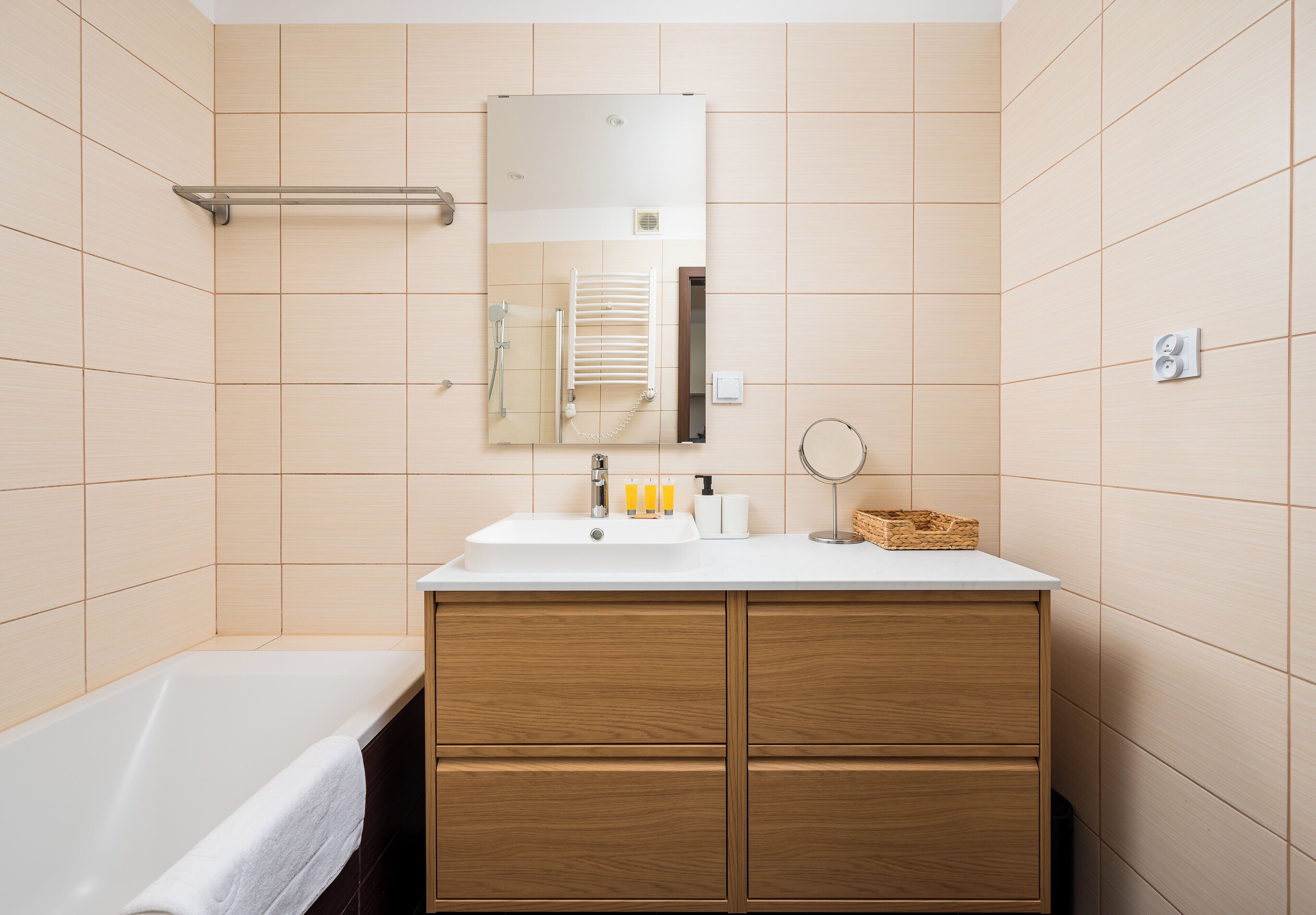 Ein Badezimmer mit einer Badewanne, einem hölzernen Waschtisch mit Spiegel und einem Handtuchhalter.