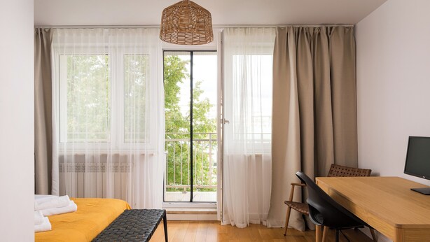 A room with a bed, a desk, a chair, and a window with curtains. - Metro Stokłosy 2-Bedroom Apartment (Warszawa)