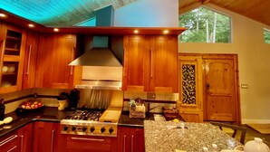Una cocina moderna con armarios de madera, una campana extractora de acero inoxidable y un ventanal que proporciona luz natural.