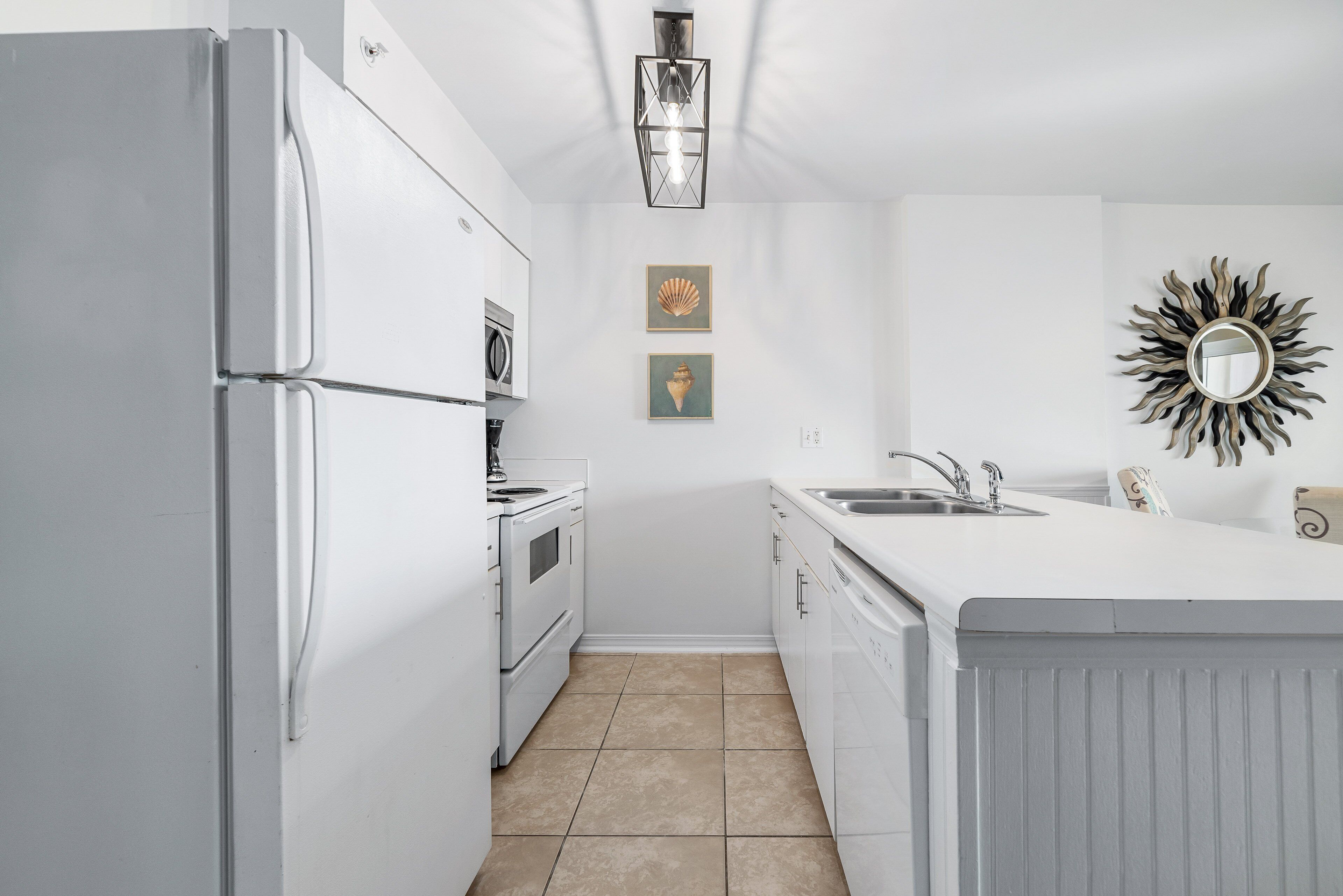 Une cuisine moderne avec des appareils électroménagers blancs, un îlot central doté d’un évier et des éléments décoratifs muraux.