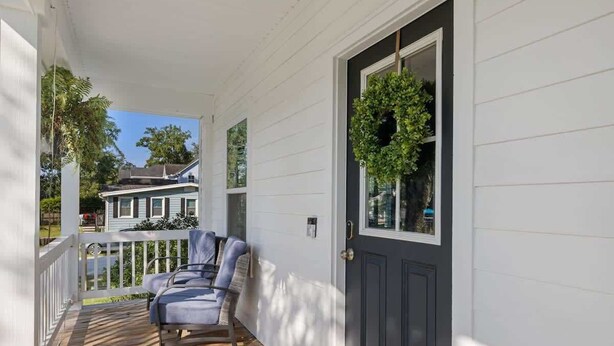 A porch with two chairs, a dark door, and a window with a plant. - Cozy Charleston Home with Putting Green (N. Charleston)