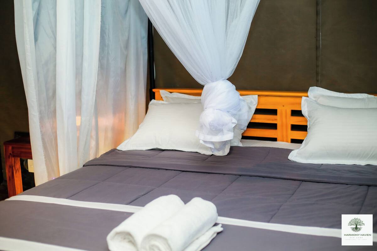 Een net opgemaakt bed met witte lakens, een houten hoofdbord en een hemelbed.