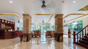 A hotel lobby with a reception desk, seating area, and a staircase. - Luxy Park Hotel & Apartments - MTown (Phu Quoc Island)