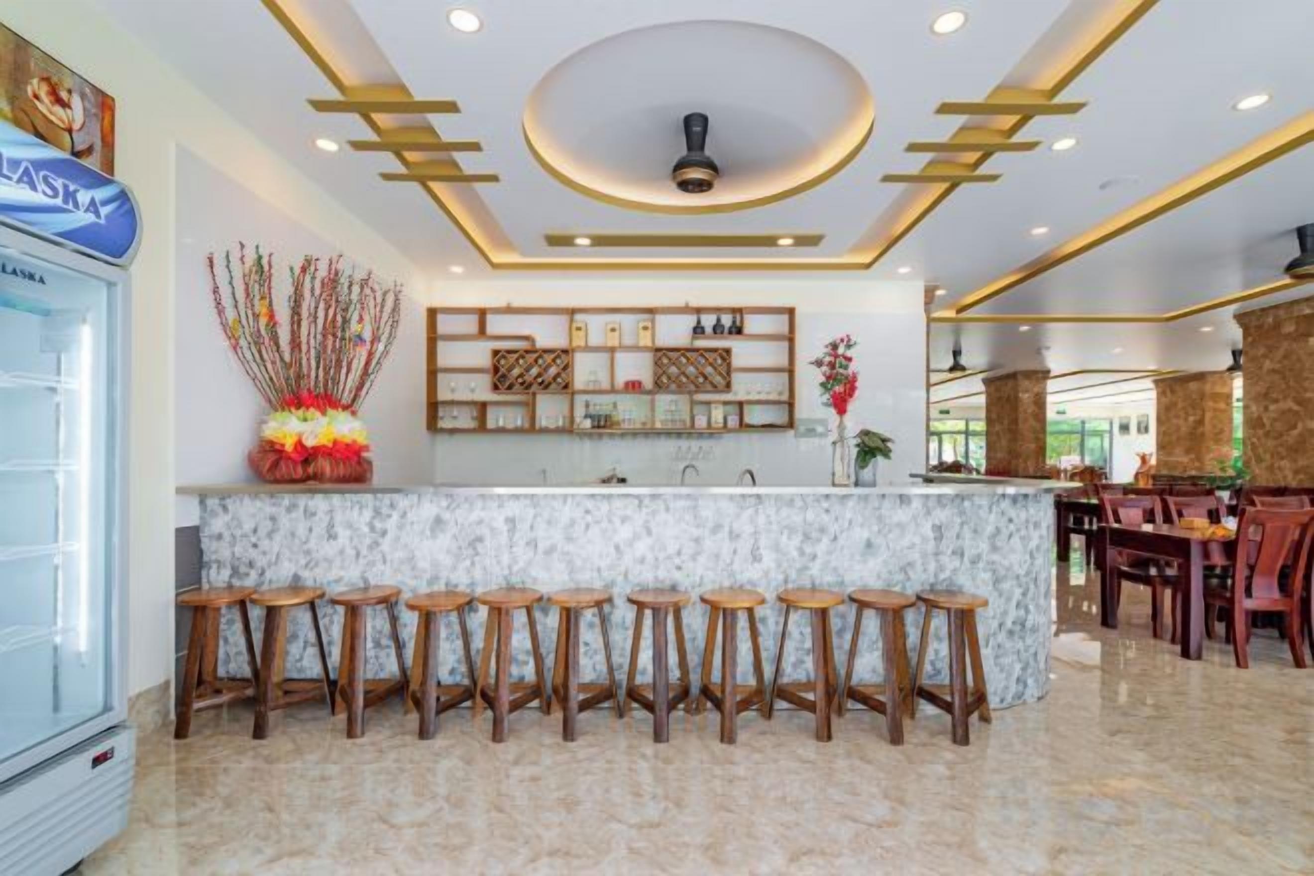 A bar area with a marble countertop, wooden stools, and a ceiling with recessed lighting.