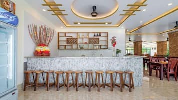 A bar area with a marble countertop, wooden stools, and a ceiling with recessed lighting.