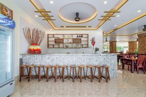 A bar area with a marble countertop, wooden stools, and a ceiling with recessed lighting. - Luxy Park Hotel & Apartments - MTown (Phu Quoc Island)