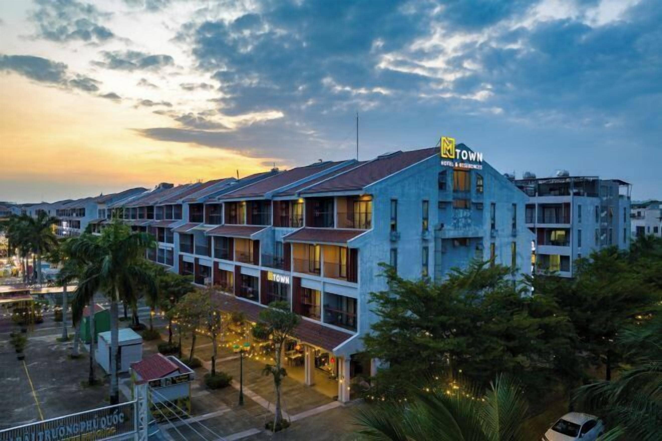 Un hotel con diversi piani, un logo 'M' ben visibile e un cartello che indica 'Hotel & Residences'.
