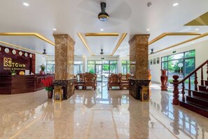 A hotel lobby with a reception desk, seating area, and a staircase. - Luxy Park Hotel & Apartments - MTown (Phu Quoc Island)