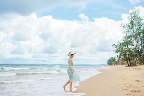 A beach scene with a person walking along the shore. - Luxy Park Hotel & Apartments - MTown (Phu Quoc Island)