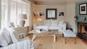 A cozy living room with a white sofa, a striped armchair, a coffee table, and a fireplace.
