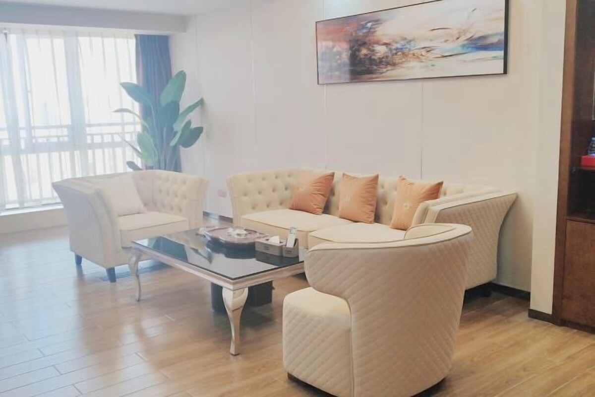 Ein Wohnzimmer mit einer Sofagarnitur, einem Couchtisch und einer großen Pflanze.