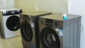 Two stacked washing machines in a room with tiled flooring. - Guanhai Holiday Hotel (Lufeng)