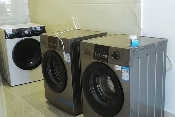 Two stacked washing machines in a room with tiled flooring. - Guanhai Holiday Hotel (Lufeng)