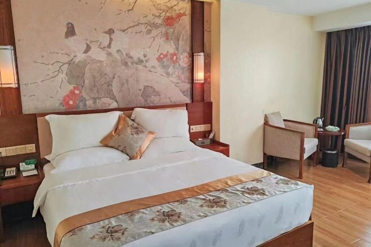 Ein Hotelzimmer mit einem großen Bett, einem Schreibtisch, einem Sessel und einem Gemälde an der Wand.