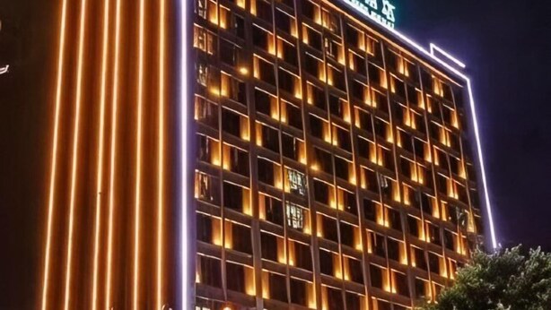 A multi-story hotel with illuminated windows and a sign in a foreign language. - Guanhai Holiday Hotel (Lufeng)