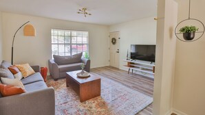 Ein Wohnzimmer mit grauem Sofa, einem Holztisch und einem Fernsehschrank.