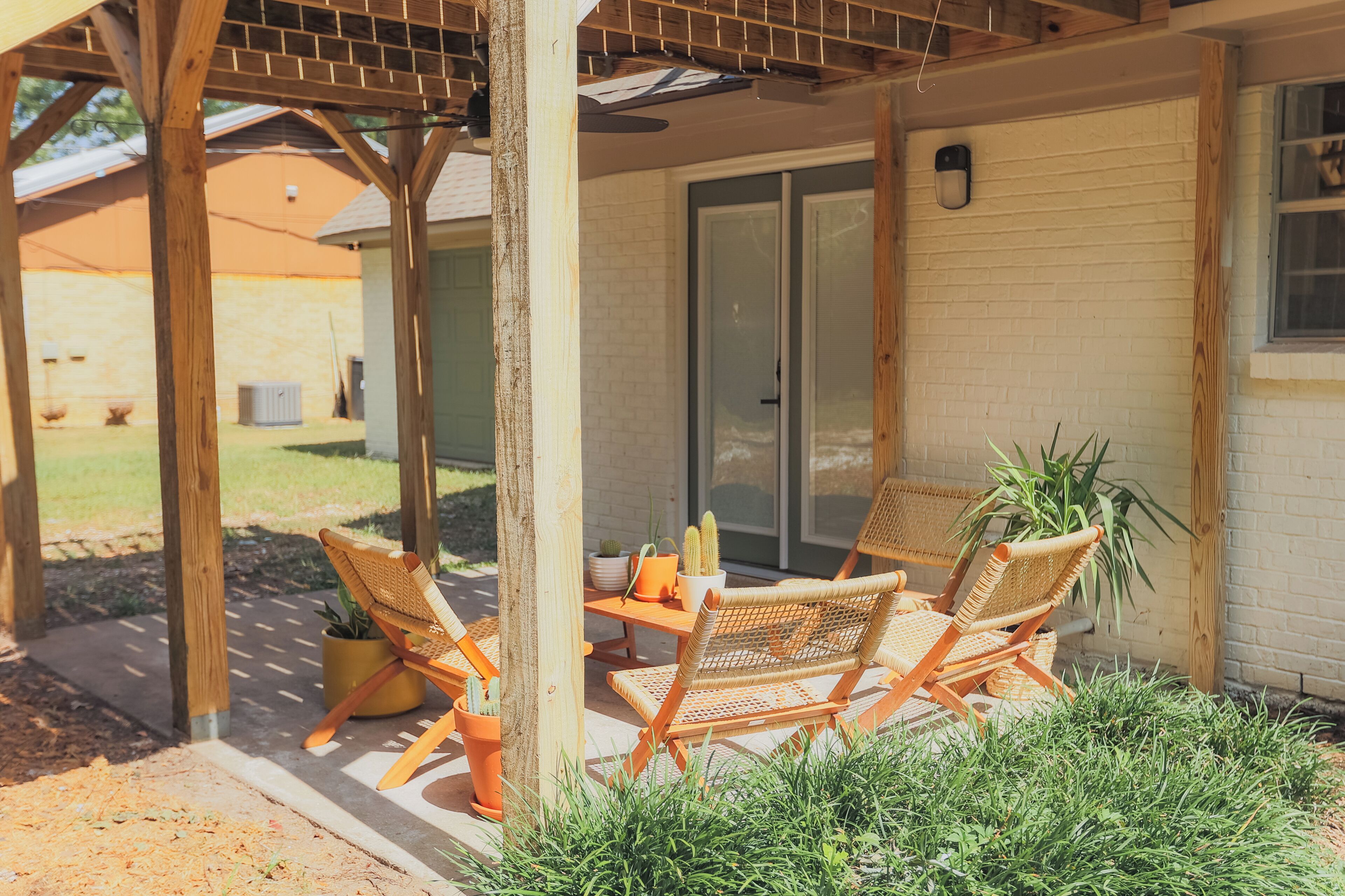 A covered patio area with wicker furniture and potted plants.