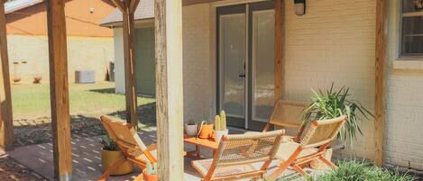 A covered patio area with wicker furniture and potted plants.