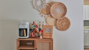 Eine Küchenzeile mit Kaffeemaschine, Tassen und einem Willkommensschild an einem Holzschrank.