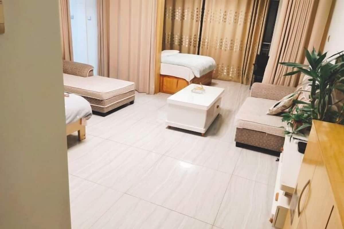 A hotel room with a bed, a sofa, a small table, and a plant.