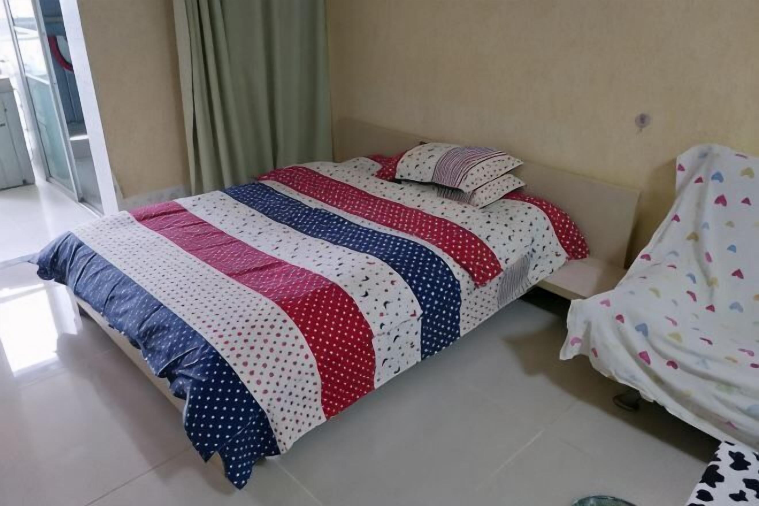 A bed with a striped bedspread, a pillow, and a blanket on a white floor.