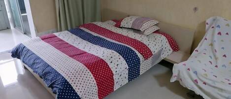 A bed with a striped bedspread, a pillow, and a blanket on a white floor.