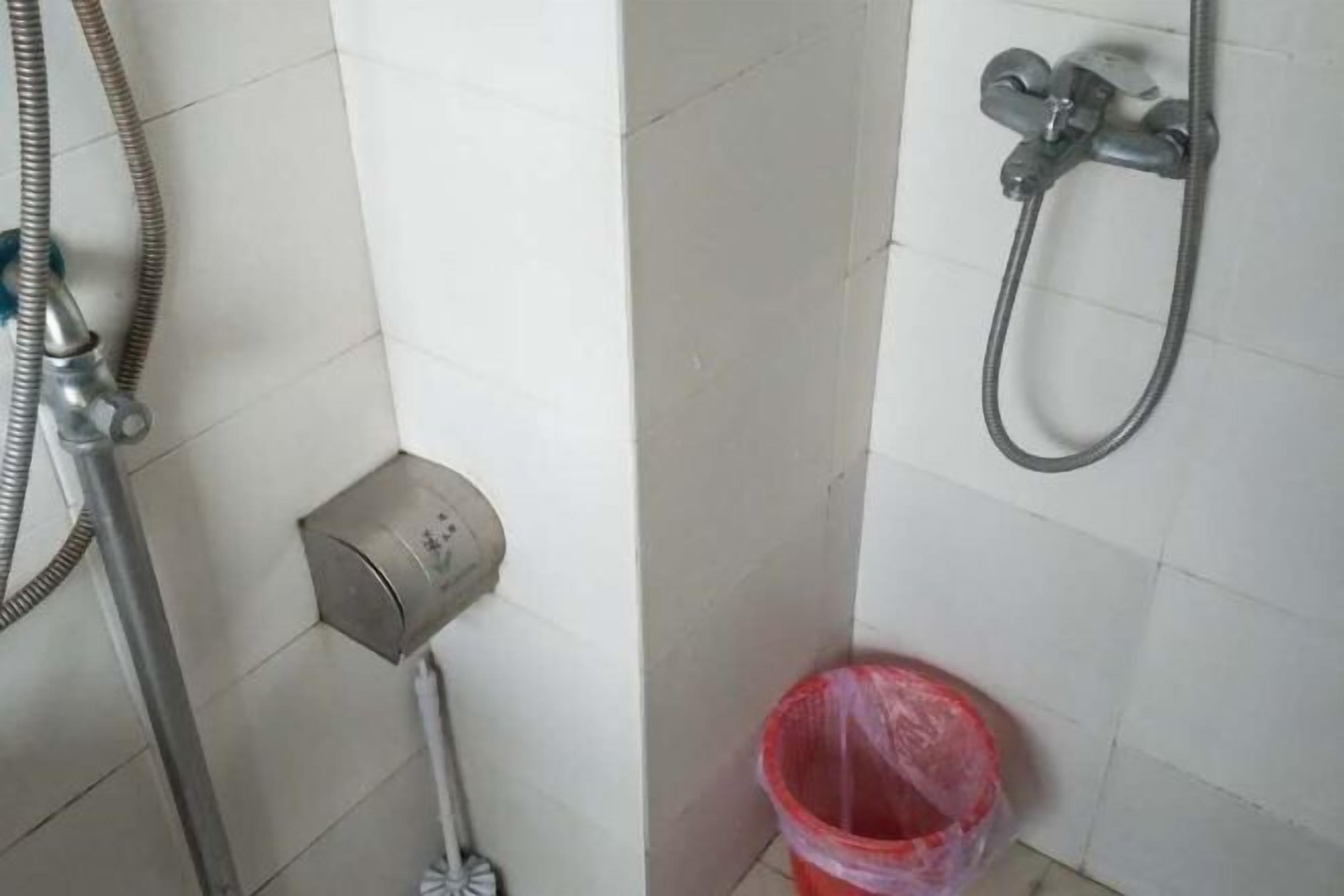 Une salle de bain équipée d’une douche, de toilettes et d’une poubelle.