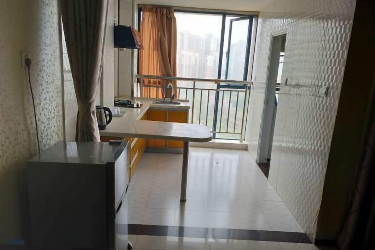 A kitchen with a dining table, a small sink, and a window with a view of buildings.