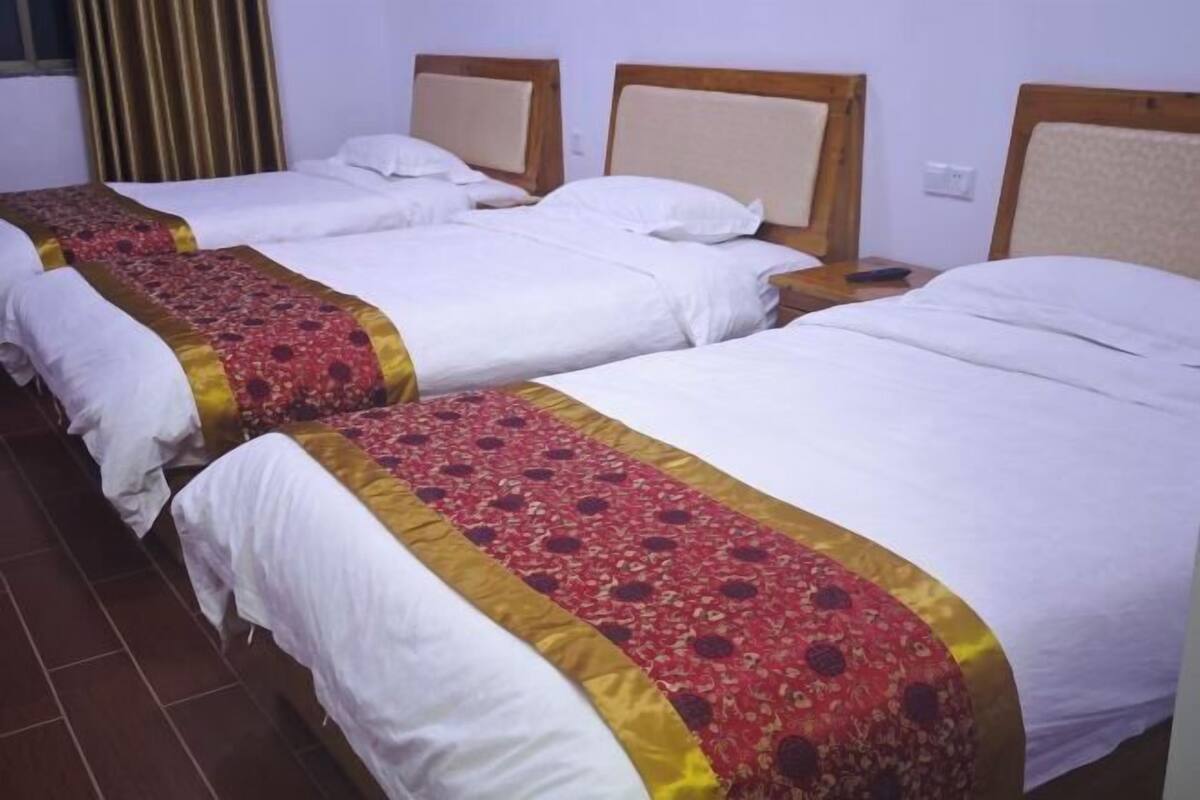 Habitación de hotel con dos camas individuales, cada una con cabecero de madera y ropa de cama blanca.