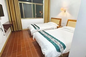Quarto de hotel com duas camas, uma janela com cortinas, uma TV fixada na parede e uma mesa de cabeceira com abajur.