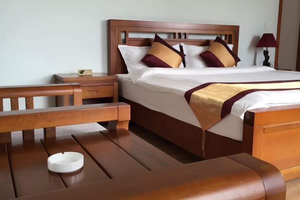A wooden bed with a headboard, a bedside table, and a lamp.