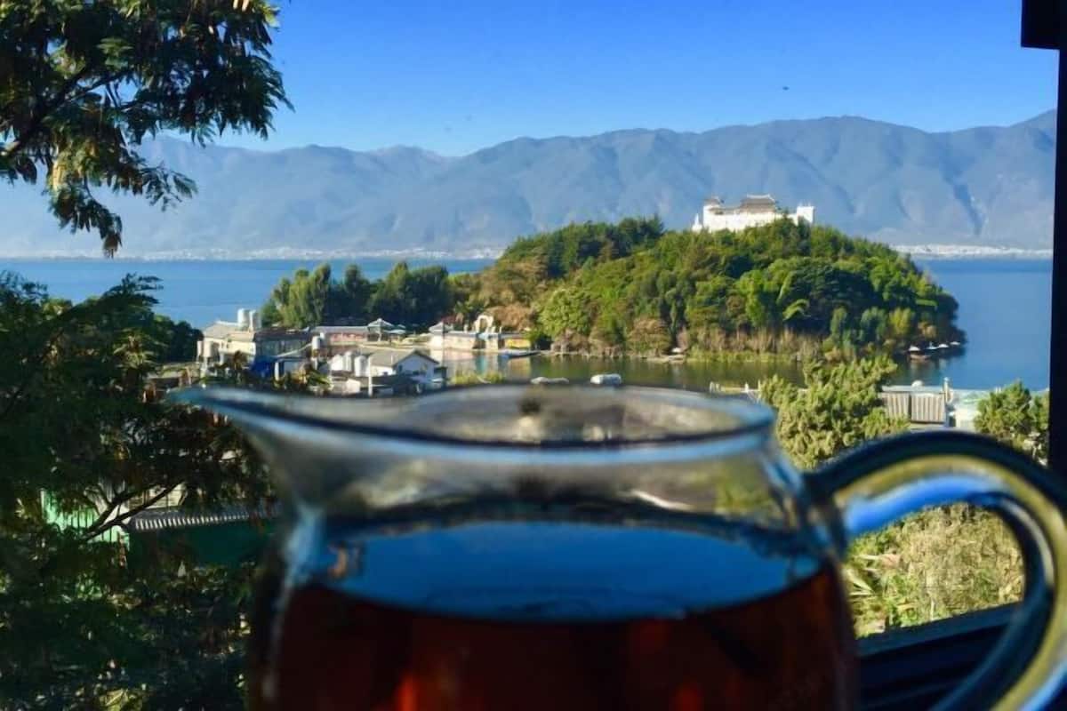 A view of a lake with a building on a hill, a clear sky, and a pitcher in the foreground.