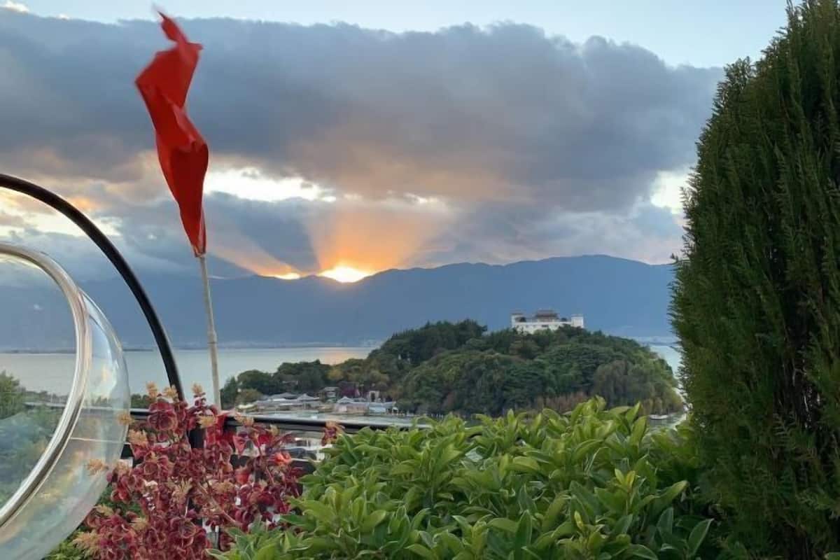 A view from a balcony with a flag, a lake, and mountains in the background.