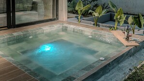 Un'area benessere con vasca idromassaggio, posti a sedere e piante.