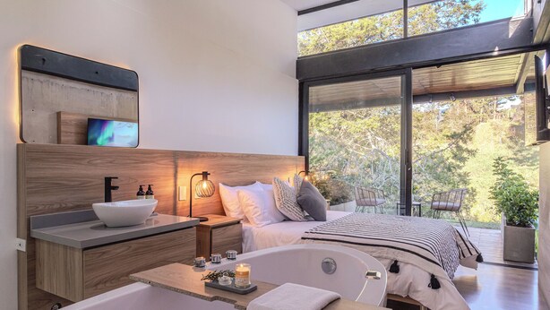 Camera moderna con un letto grande, una vasca da bagno e un comò in legno con lavandino.