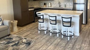 A modern kitchen with a central island, bar stools, and built-in appliances.