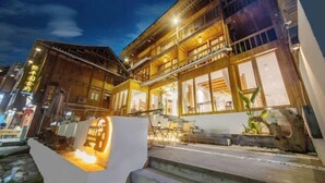 A traditional wooden building with multiple balconies and large windows, likely a hotel or guesthouse. - Zhaoxing Dong Village at that time, flowers blossoming, live music, courtyard homestay (Liping)