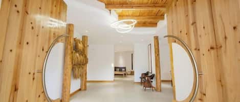 A hallway with wooden walls and ceiling, a circular mirror on the left, and a circular mirror on the right.